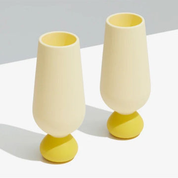 Two yellow and white silicone champagne glasses on a light gray background.