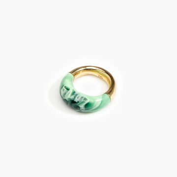 A brass ring half covered with moss green resin.