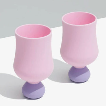 Two pink and purple silicone goblets on a white surface with a gray background
