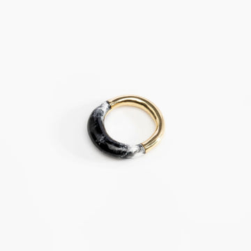 A brass ring half covered with black marble resin.