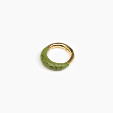 A brass ring half covered with moss green resin.