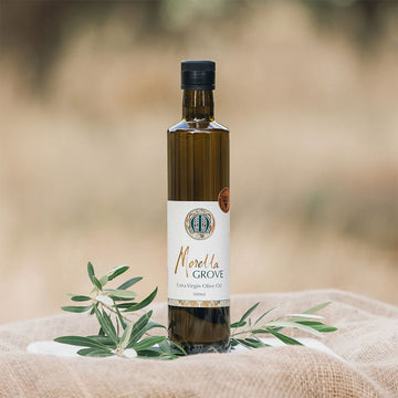A bottle of extra virgin olive oil on a linen cloth and a plant.