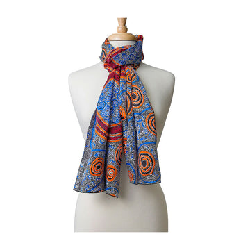 A silk scarf printed with artwork in orange and blue wrapped around the neck of a mannequin.