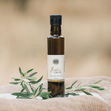 A bottle of extra virgin olive oil on a linen cloth and plant.