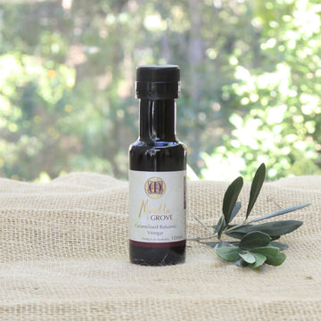 A small bottle of balsamic vinegar on a linen cloth next to a plant.
