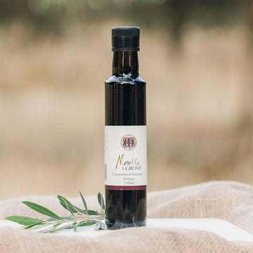 A bottle of balsamic vinegar next to a plant stem.