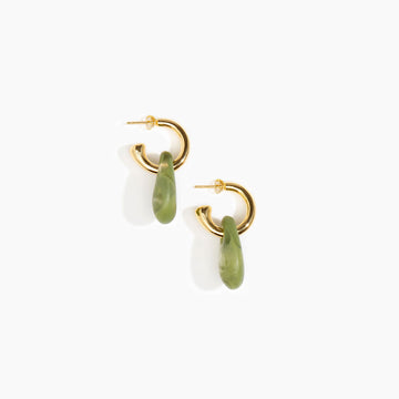 A pair of brass hoop earrings with large olive green resin beads hanging off the hoop.