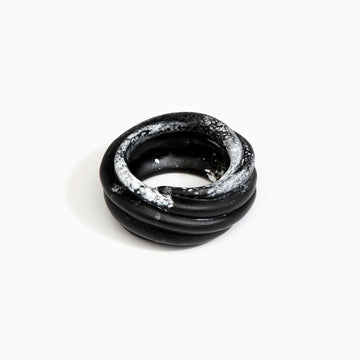 A resin bangle in black marble with a spiral shape.