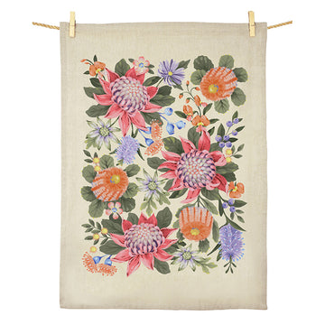A cotton tea towel printed with colourful flowers is hanging off a rope.