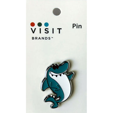 Shark-shaped pin on a white card with 'Visit Brands' branding.