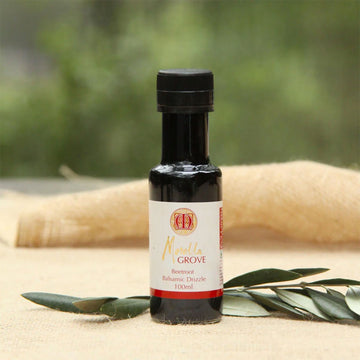 A bottle of beetroot balsamic drizzle with leaves behind it.