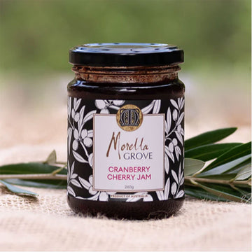 Jar of Cranberry Cherry Jam from Morella Grove with a decorative label on a natural background.
