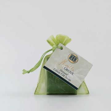 A green organza bag with a bar of soap inside and a label that says 'Natural Olive Oil Soap'.