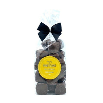 A clear bag filled with chocolate covered honeycomb with black bow at the top and a yellow product label with the text 'Honeycomb'.