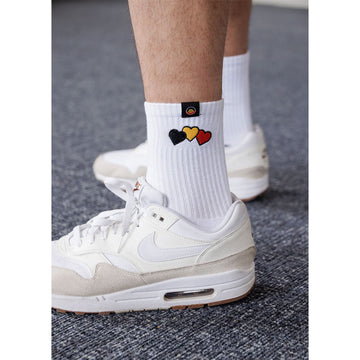 A pair of black and white socks embroidered with a black, yellow and red heart.
