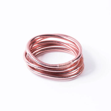 A stack of rose gold bracelets made from leather.