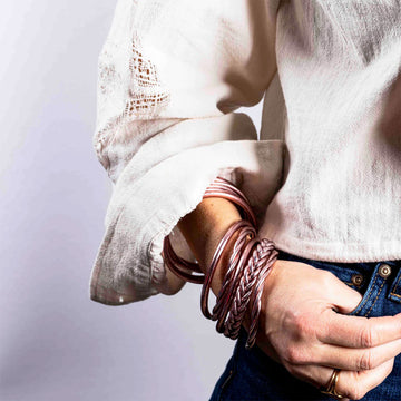 A stack of twist style bracelets in rose gold.