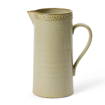 A ceramic jug in green with an embossed leaf border around the top edge.