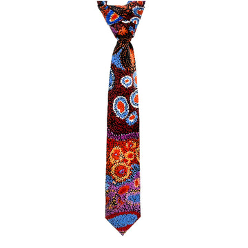 A tie is hanging and printed with artwork by Andrea Mimpitja Adamson in yellow, red, blue and brown.