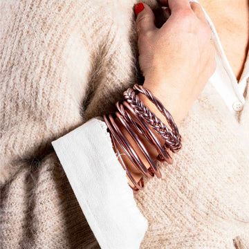 A stack of braided bracelets in rose gold.