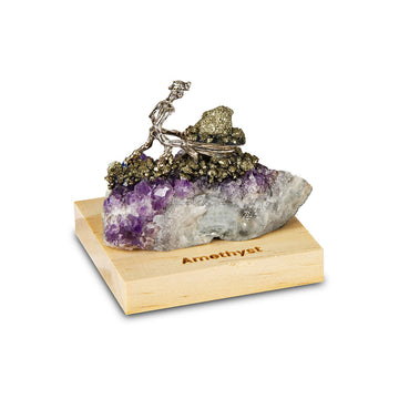 A wood block with an amethyst stone and a miner sculpture on top.