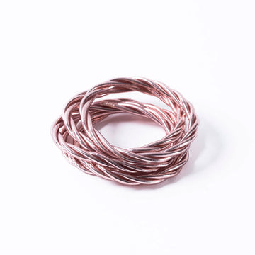 A stack of twist style bracelets in rose gold.