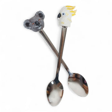 A pair of spoons with a koala head and a cockatoo head on the ends.