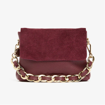 A small burgundy bag with a suede flap over the leather bag. It also has a short gold chain strap.