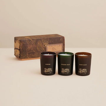 Three scented candles with packaging box on a beige background.