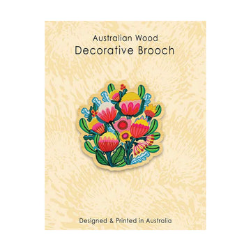 A wooden brooch illustrated with flowers on a card backing.