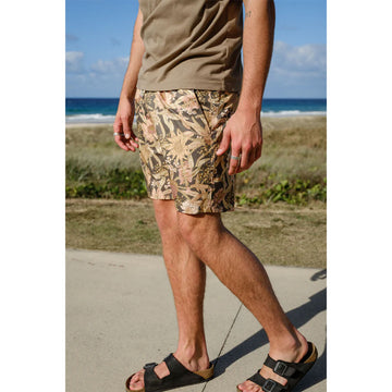 Close up front view of a man wearing a khaki green tshirt with banksia printed shorts.