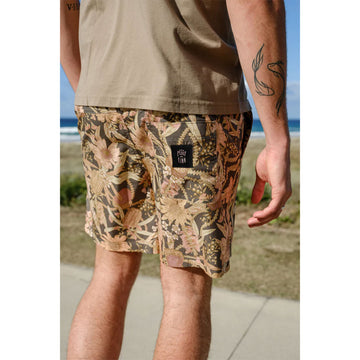 Close up front view of a man wearing a khaki green tshirt with banksia printed shorts.