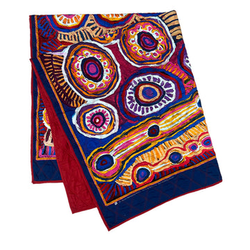 A quilted blanket printed with artwork by Murdie Morris on the front and red on the back.