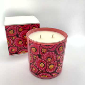 A candle and matching box printed with artwork in red and yellow.