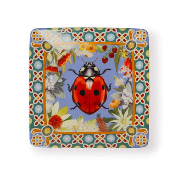 A ceramic square trinket dish printed with an illustration of a ladybug with a floral border. 