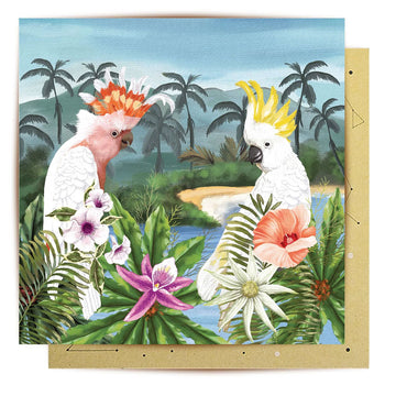 Card with two cockatoos and tropical flowers on a scenic background.
