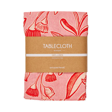 A folded up tablecloth printed with a red and pink floral pattern and a cardboard sleeve.