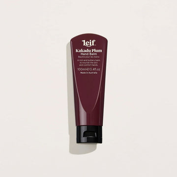 A tube of hand cream in dark burgundy with a black lid and white text titled 'Kakadu Plum Hand Balm'.