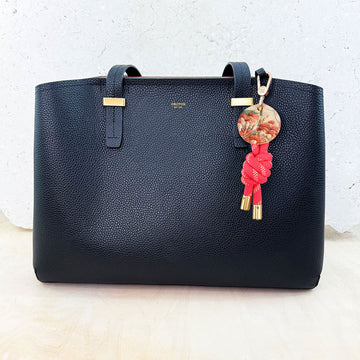 Keychain with pink rope and gold accents on a white background.