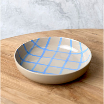 Ceramic bowl with blue grid pattern on a wooden surface.