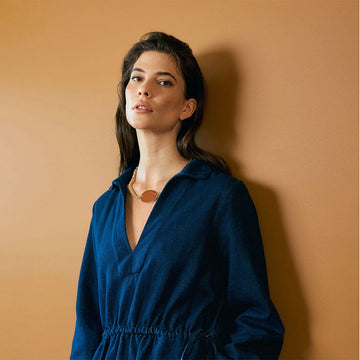 An image of a gold necklace with a gloss oval pendant in a deep spice colour.