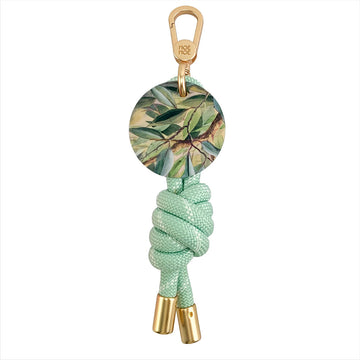 Keychain with green rope and leaf-patterned disc on a white background