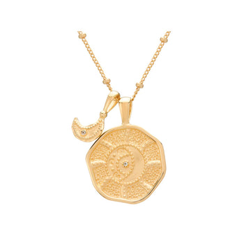 A gold plated necklace with a large rounded pendant and a smaller crescent moon pendant on a chain.