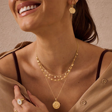 A round pendant in gold with etchings on a gold chain.