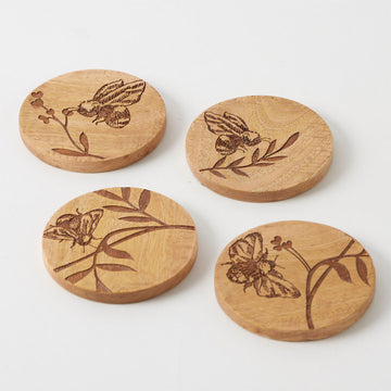 A set of four round wooden coasters each etched with a different bee design.