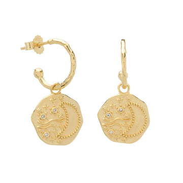 A pair of gold hoop earrings with a hexagon shaped pendant hanging off the hoop with an outline of a crescent moon.