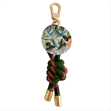 Keychain with green rope, gold accents, and floral design on a white background.