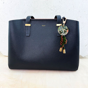 Keychain with green rope, gold accents, and floral design on a white background.