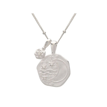 A silver necklace with a hexagon shaped pendant with an outline of a crescent moon.