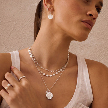 A silver necklace with a hexagon shaped pendant with an outline of a crescent moon.